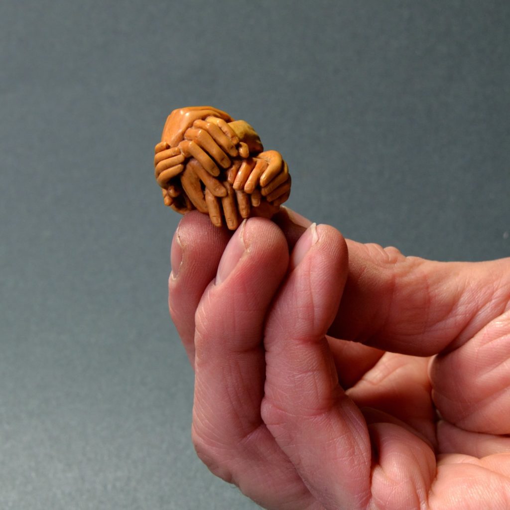 A contemporary netsuke carved from boxwood, depicting a bundle of hands