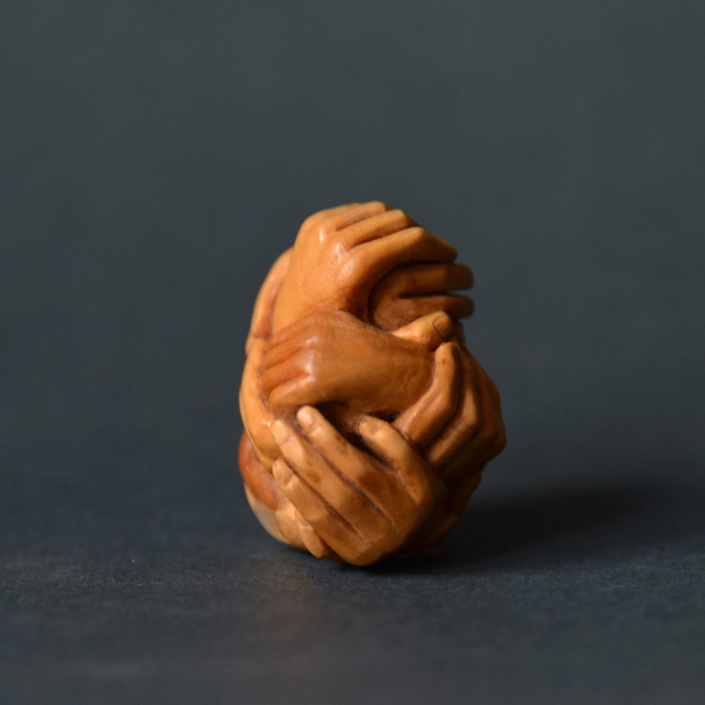 A contemporary netsuke carved from boxwood, depicting a bundle of hands